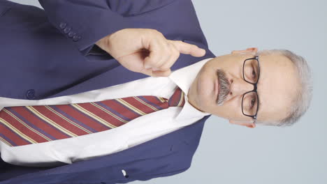 Vertical-video-of-Old-businessman-alerting-camera-with-stern-expression.