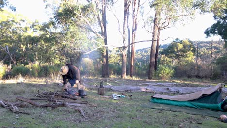 A-bushman-puts-a-billy-on-the-boil-with-his-swag-set-up-in-the-Australian-bush