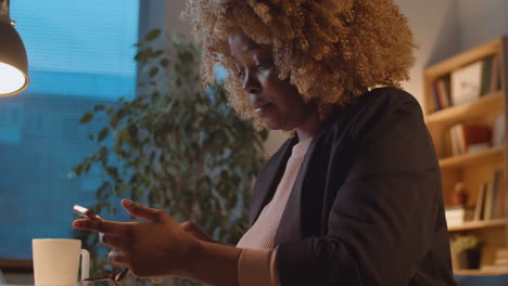african american businesswoman messaging on phone in office