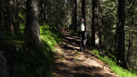 Man-hiking-alone-in-dark-forest-with-large-backpack,-Slow-Motion