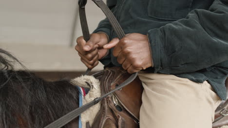 cerca de la mano de un hombre montando un caballo marrón