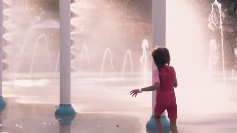 little girl runs in fountain jets in aquapark slow motion