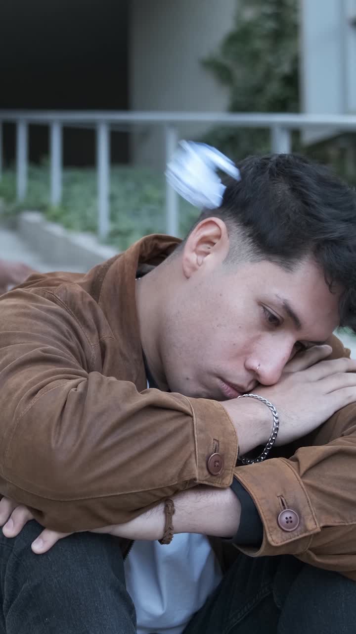 A group of students bulling an hispanic man sitting on the stairs outdoors
