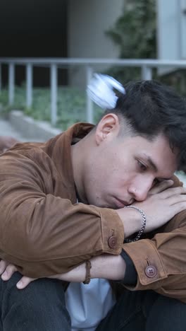 a group of students bulling an hispanic man sitting on the stairs outdoors