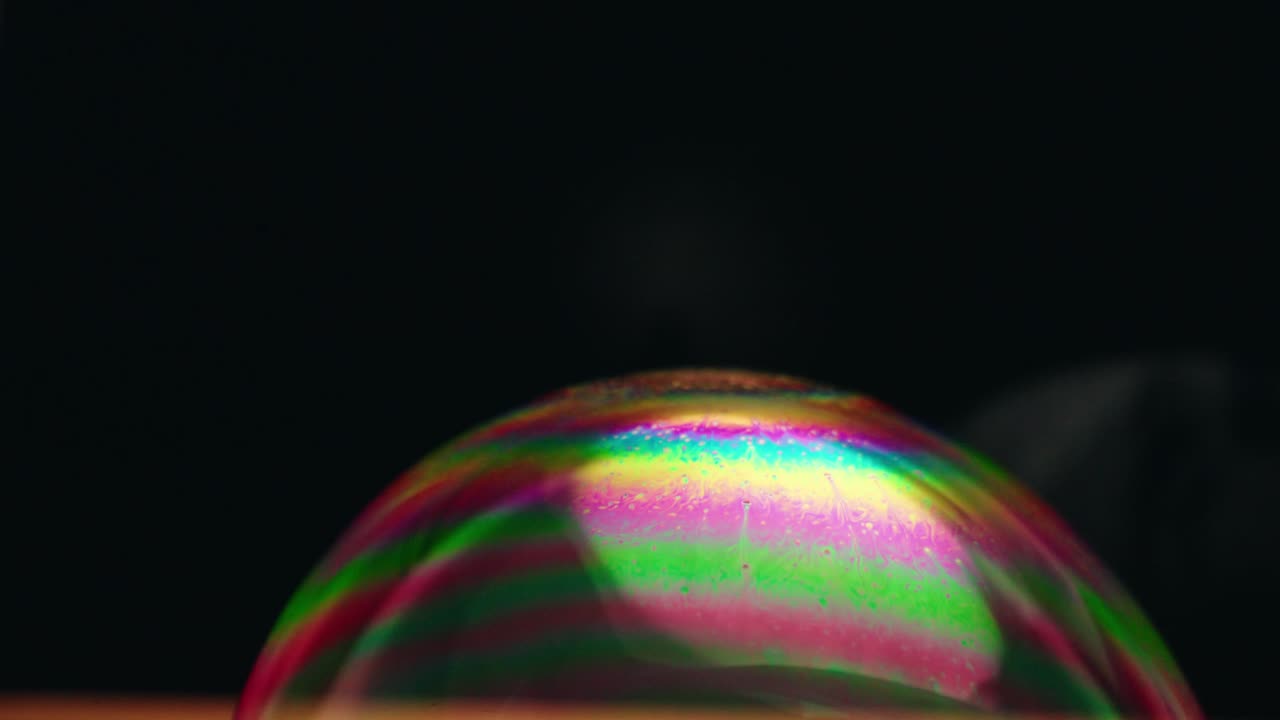 Close-up view of a rainbow-colored soap bubble with horizontally rotating color spectrum, Canada.