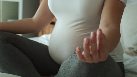 Video-of-pregnant-woman-meditating-while-sitting-on-bed.