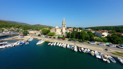 drone soars swooping fpv through sailboat masts over town city center of osor croatia