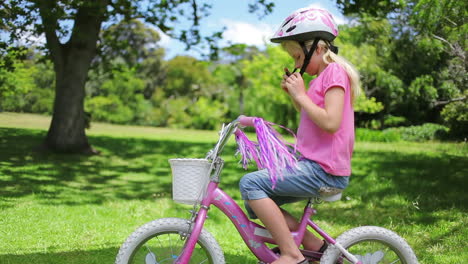una chica saca su casco de una canasta de bicicleta y se lo pone en la cabeza mientras se sienta en la bicicleta