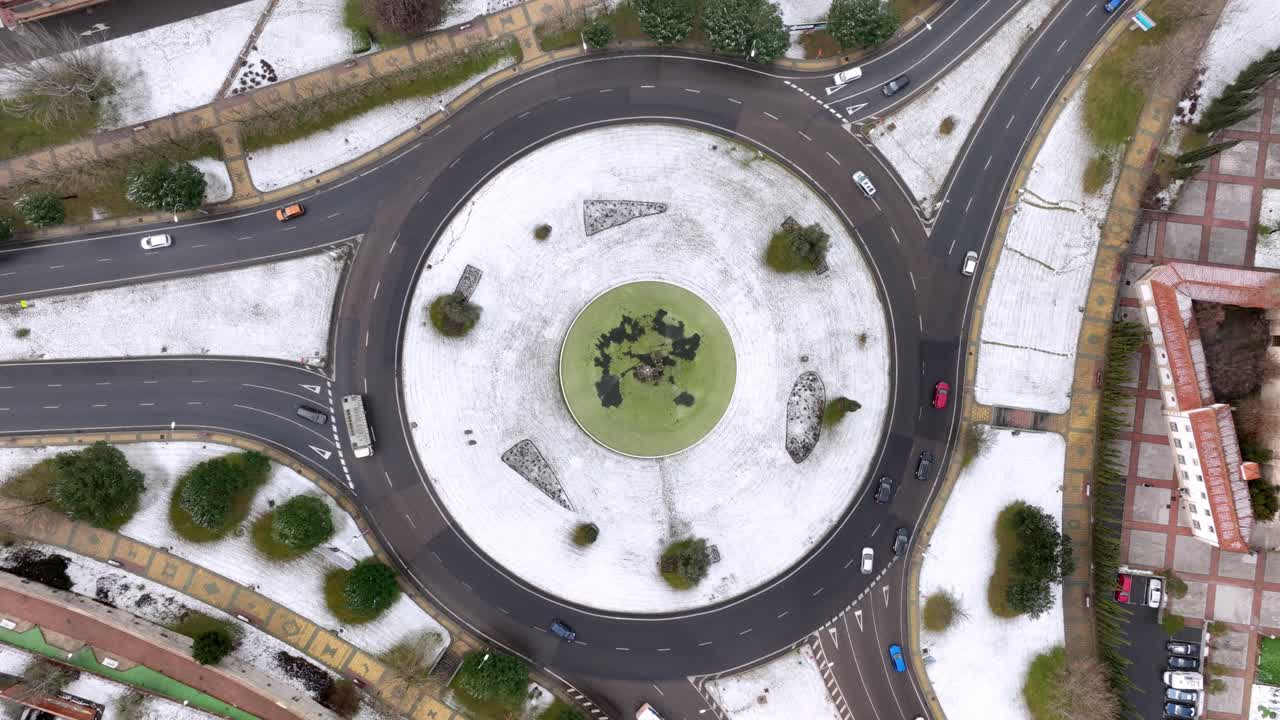 vista aérea de una rotonda cubierta de nieve y rodeada de tráfico.