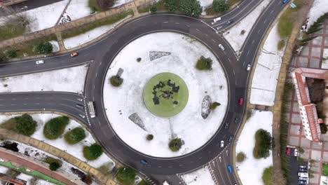Aerial-view-of-a-roundabout-covered-in-snow-and-surrounded-by-traffic
