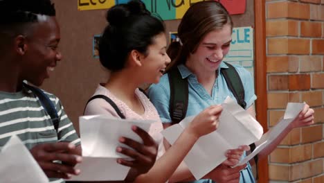 compañeros de clase felices mirando las tarjetas de calificación en el pasillo