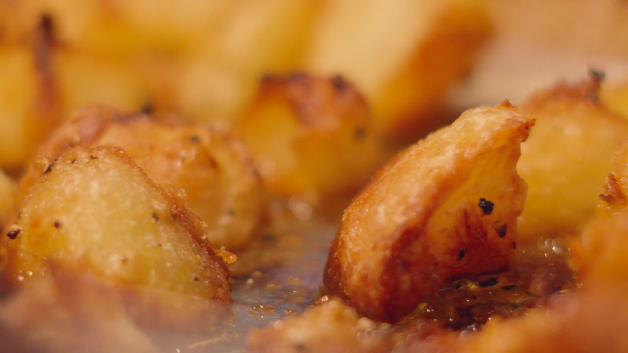 Slow Pan Across Delicious Crispy Golden Roast Potatoes with Pepper Seasoning. Roasted Food Served Traditionally on Sunday in Britain