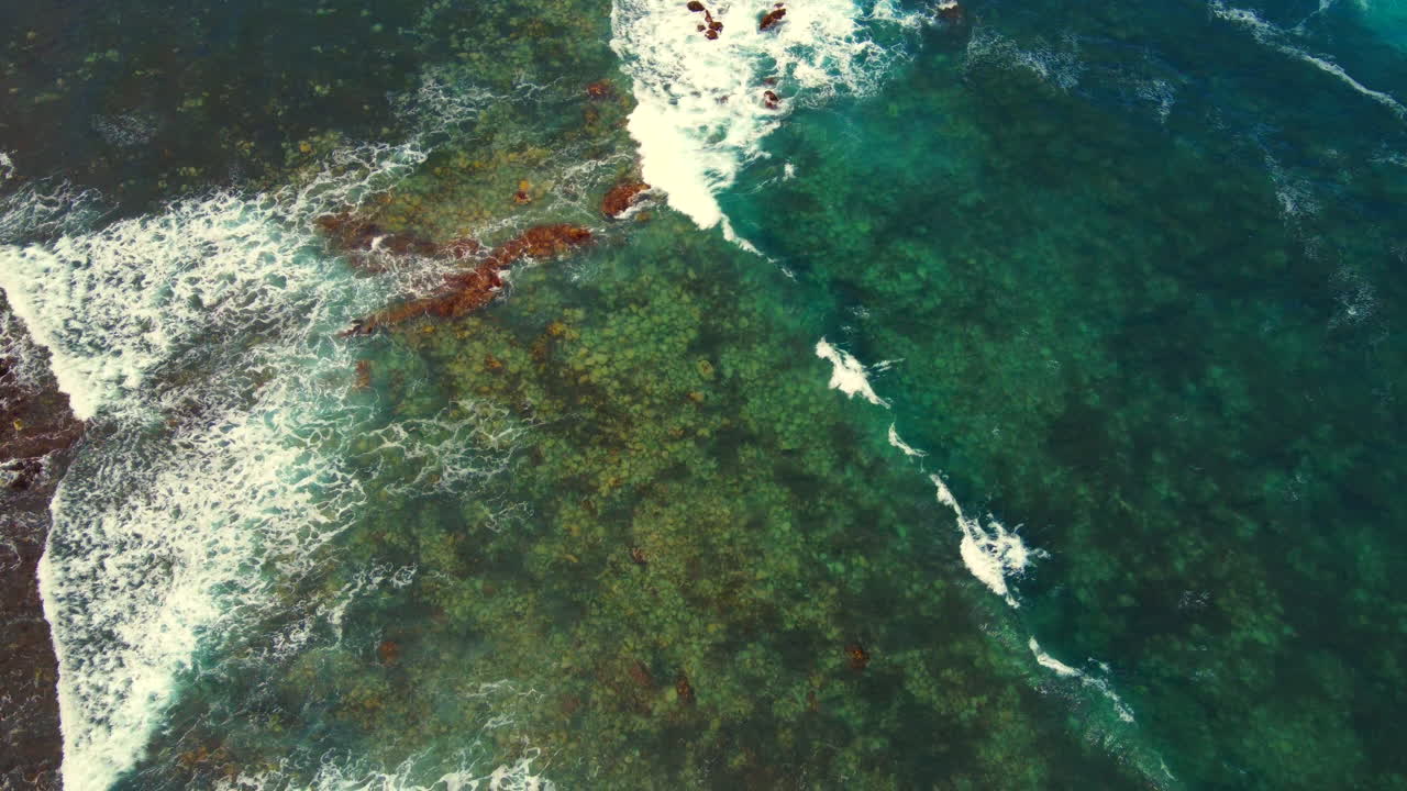 vídeo aéreo indo para baixo e vendo as ondas no oceano batendo contra as rochas na praia