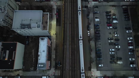 aerial view above a train driving on elevated rails in illuminated new york, usa - top down, drone shot