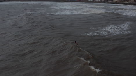 Aerial-view-of-a-man-on-a-surfboard-moving-across-waves.-Surfer-floating-on-the-top-of-waves-in-Bali