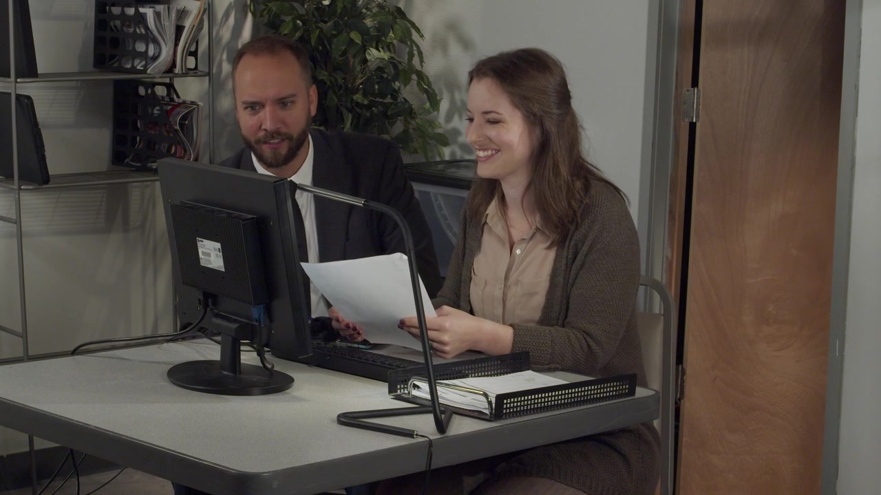 Uomo e Donna d'Affari Discutono un Progetto Mentre Lavorano al Computer