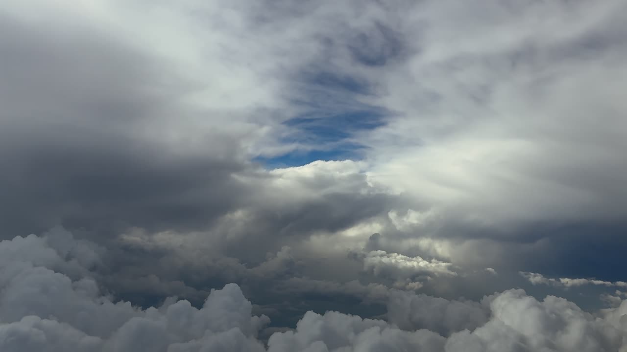 An immersive aerial view of a stormy cloudscape with white cottony stom clouds and ethereal broken clouds above in a blue sky. Ultra-realistic 4K