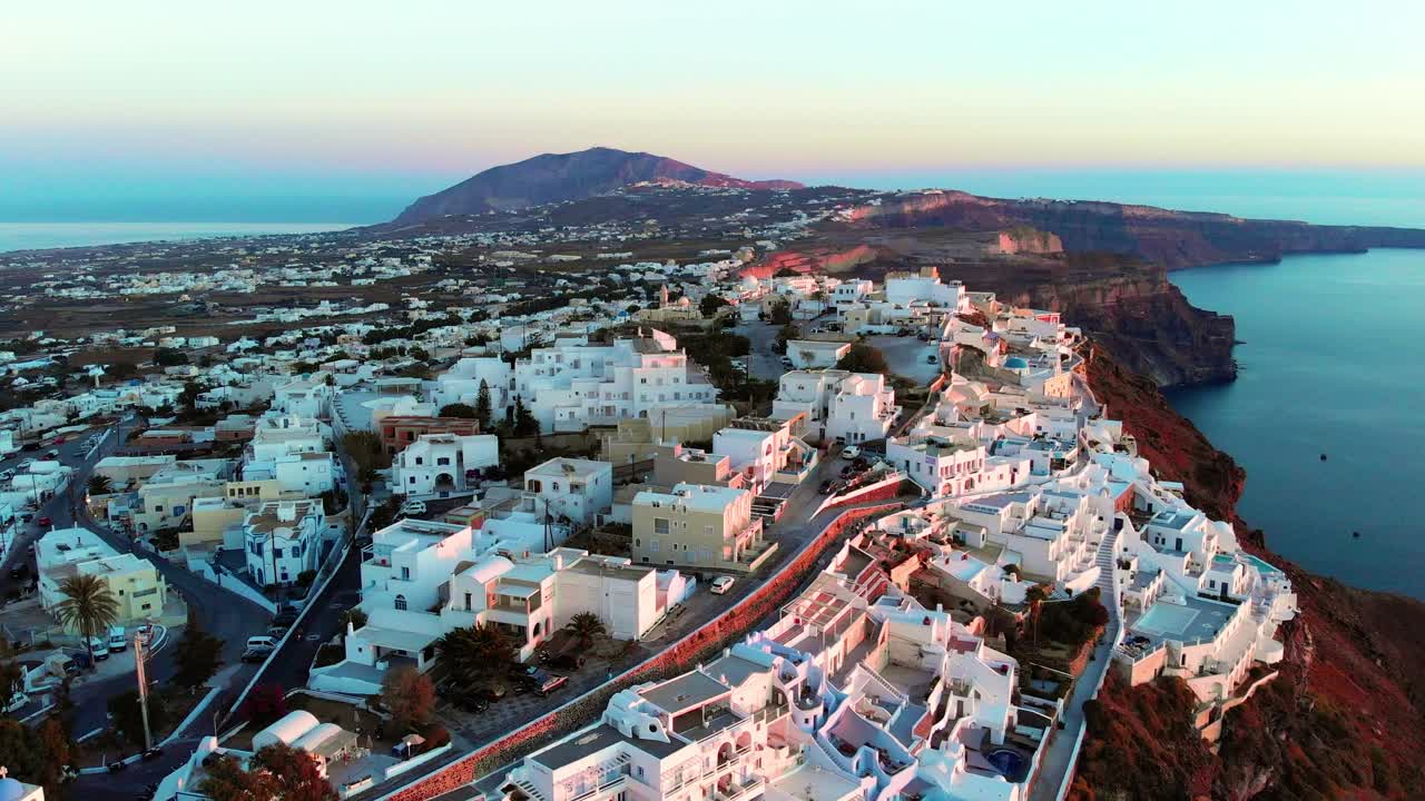 toma aérea cinematográfica del famoso pueblo de oia en santorini, grecia, al atardecer