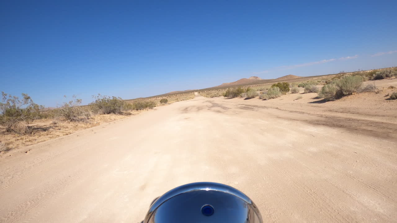 Un giro in moto caldo e solitario attraverso il paesaggio selvaggio del deserto del Mojave nel calore del giorno - punto di vista del motociclista
