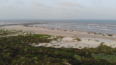 elevated static view of the grass, dunes, jetty, and ocean