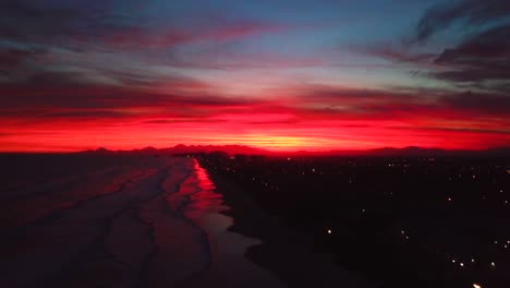 establishing slow aerial shot of late evening sunset in ocean beach of itanhaem, crazy color sky in brazil