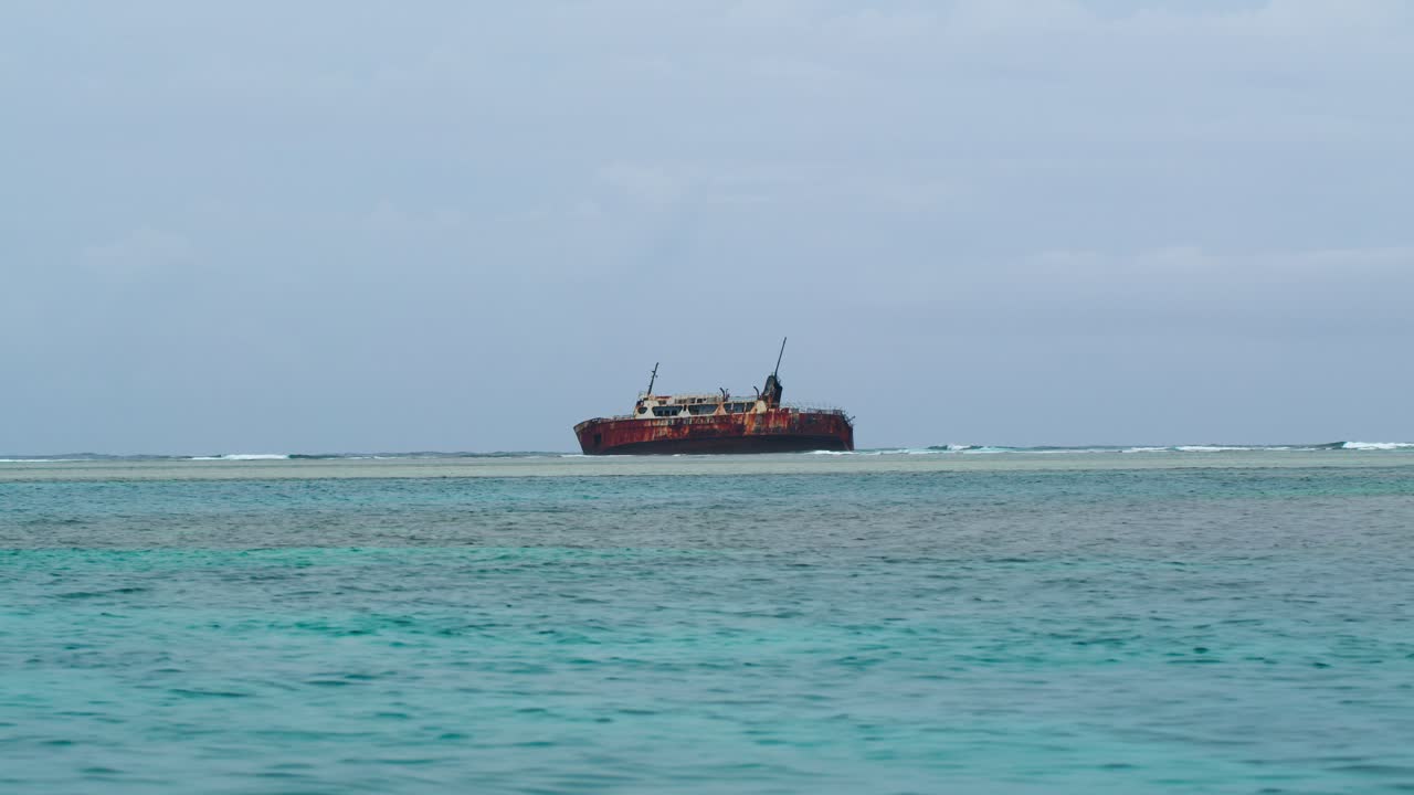 A static shot of a wrecked boat floating in the middle of the transparent Caribbean Sea, near Chichime Island in Panama’s San Blas archipelago