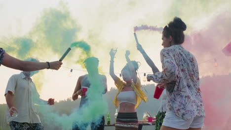 amigos bailando con bombas de humo de colores en el muelle del lago