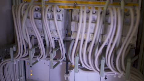 Camera-tilt-down-in-a-server-room-with-many-white-cables,-blinking-yellow-lights