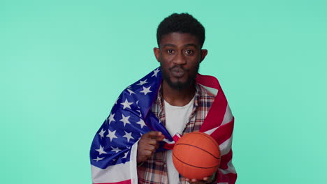 un joven barbudo fanático del baloncesto sosteniendo la bandera de los estados unidos haciendo el gesto del ganador, bailando solo