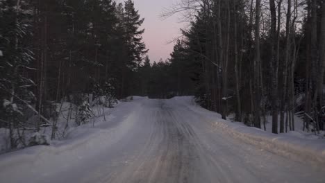 vehicle driving through snowy landscape in winter evening - pov