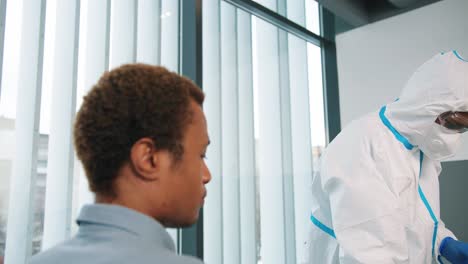 Cierre-De-Un-Trabajador-Médico-Especialista-En-Laboratorio-Con-Uniforme-Protector-Y-Máscara-Médica-Tomando-Muestras-De-Coronavirus-De-Un-Paciente-Masculino-Para-La-Prueba,-Haciendo-Pruebas-De-PCR-En-El-Gabinete-De-La-Clínica