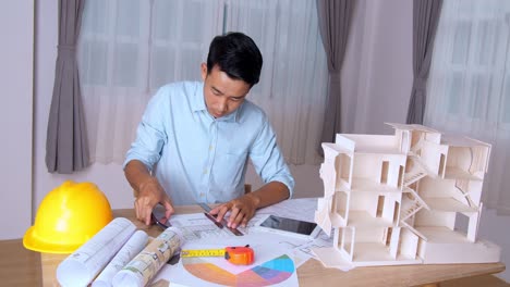 young asian architect man talking on phone and celebrating success with an architectural project