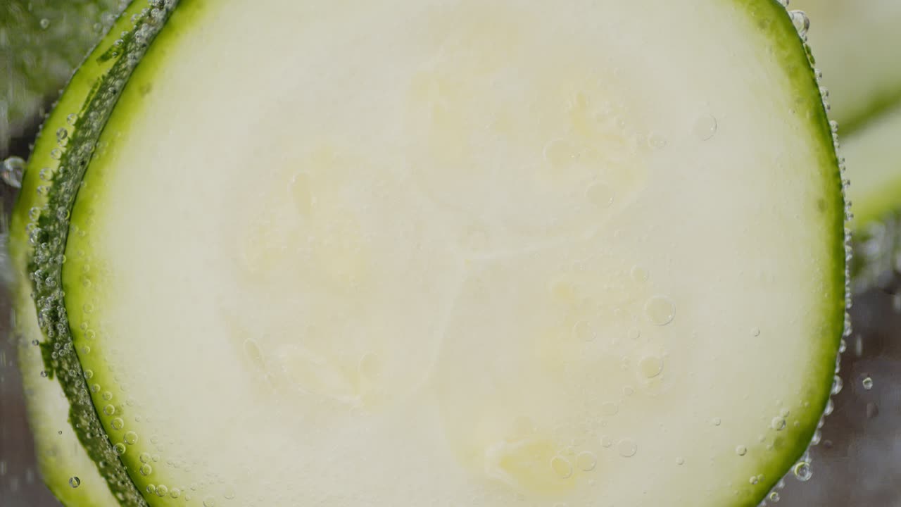 pedazos de calabacín joven bajo el agua con burbujas de aire.