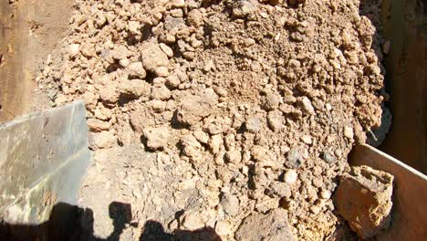 pov from excavator bucket scooping and moving dirt at site during the day