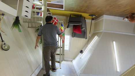 man walking through a room with upside-down furniture in a quirky, illusionary house