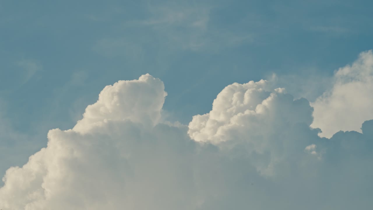 Close-up of soft, cotton-like cumulus clouds drifting across a vivid blue sky, creating a calm, airy atmosphere and a clean natural background