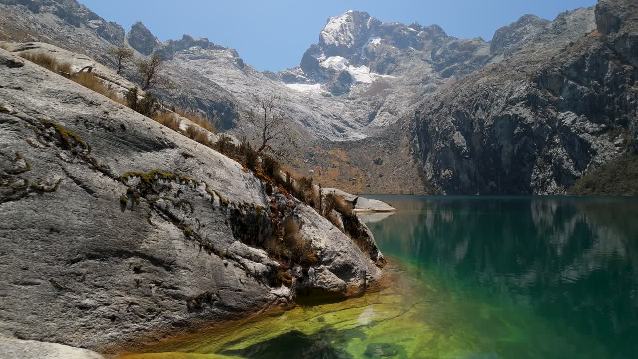 A slow aerial forward shot reveals the turquoise waters of Laguna Churup set beneath rugged Andean peaks and glaciers in Cordillera Blanca, Peru