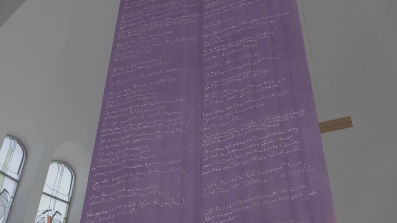 Purple banner with a prayer hangs in the sanctuary of a church in front of a cross