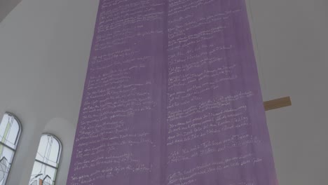 purple banner with a prayer hangs in the sanctuary of a church in front of a cross