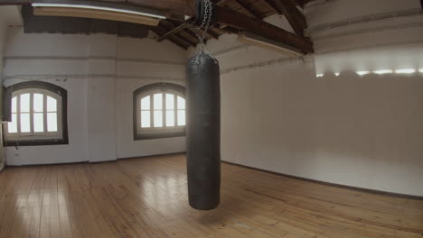 long shot of leather punching bag hanging from ceiling on chains