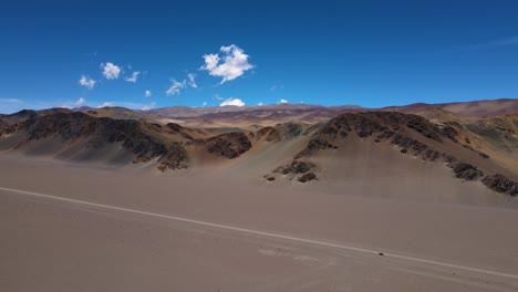 Drone-shot-flying-over-a-plateau-towards-the-Andes-mountains-in-the-desert-in-Catamarca,-Argentina