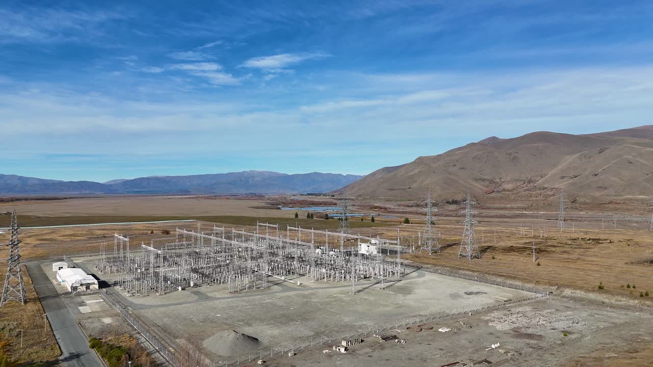 Aerial footage of a power substation at Lake Tekapo, New Zealand, showcasing high-voltage infrastructure against a mountainous autumn landscape
