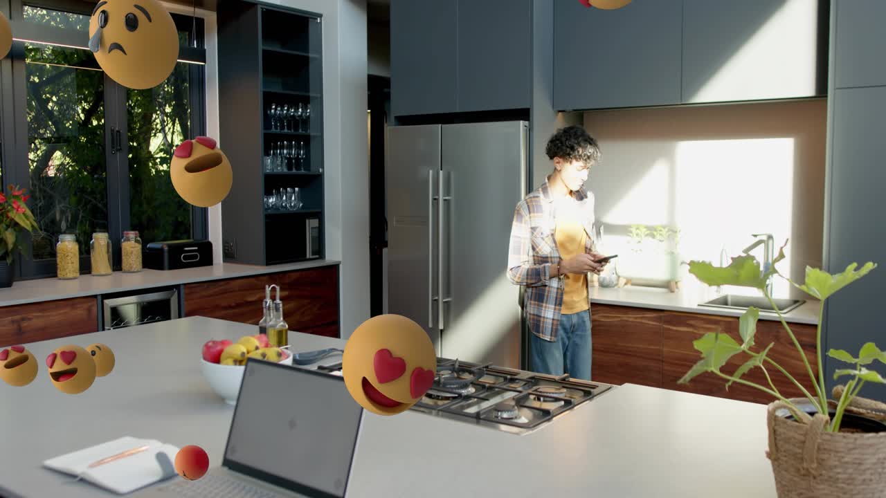 Man using phone in kitchen showing AR causing emojis emerging from right, growing, filling space