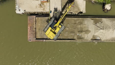 Yellow-Excavator-Unloading-And-Transferring-Sand-From-The-Carrier-Barge-In-Van-Buren,-Arkansas,-USA