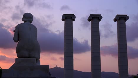 동상은 스페인 바르셀로나 시내의 로마 기둥 근처에 앉아 있습니다.