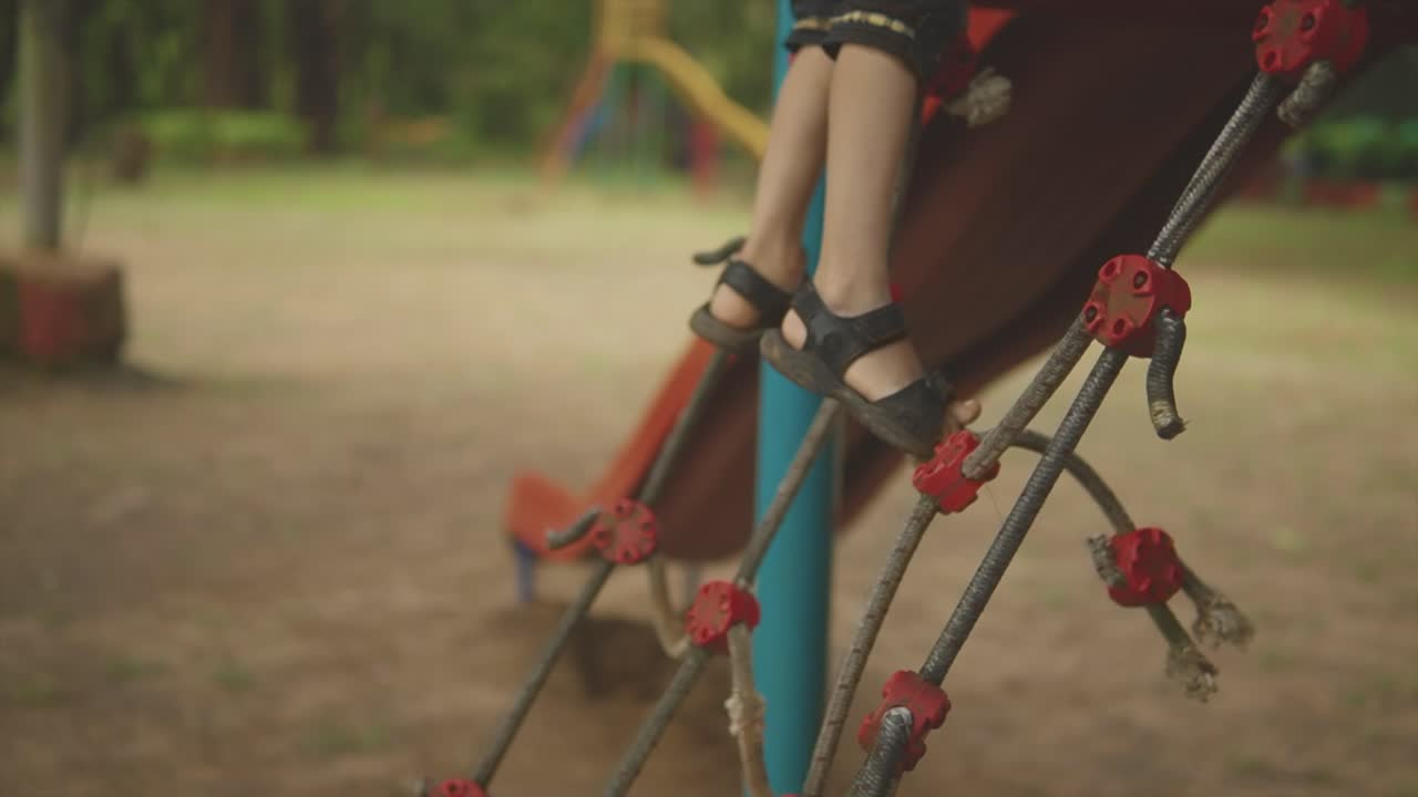A cheerful and determined young child fearlessly climbs the rope in the lively kids' garden, showcasing their strength and enthusiasm for outdoor exploration
