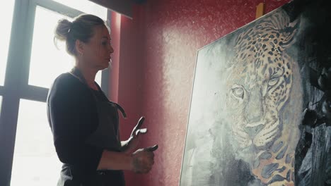 woman artist viewing a leopard painting in studio