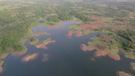 drone shot over river with greenery trees and camping on muddy red soil, grassy land
