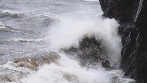 rough waves during a storm crashing onto rocky coastal cliffs in slow motion