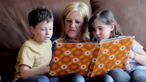 cheerful grandmother reading book to children